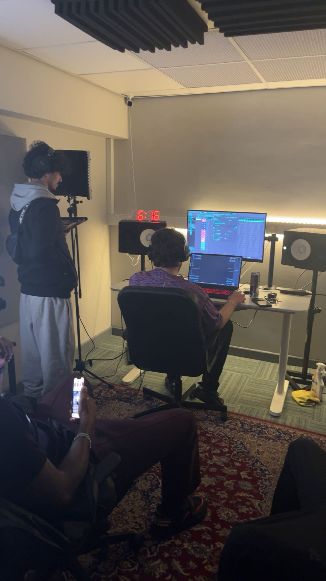A group session in the control room, one person at the mic and one at the desk
