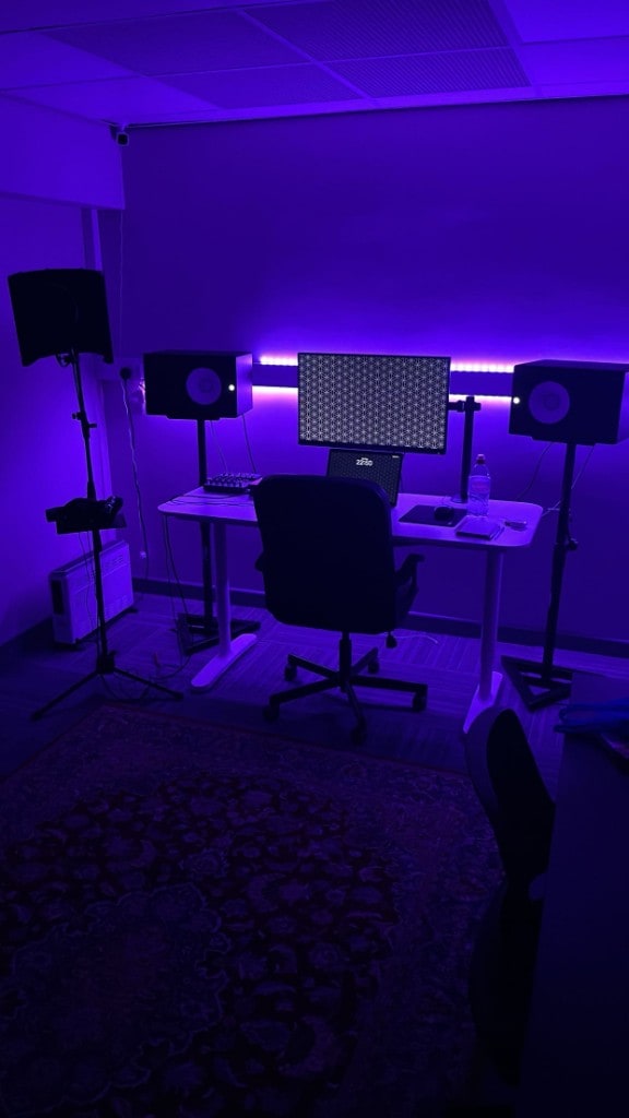 Warrington Music Studio control room with purple LED lighting, studio monitors, vocal shield, and ergonomic desk setup.